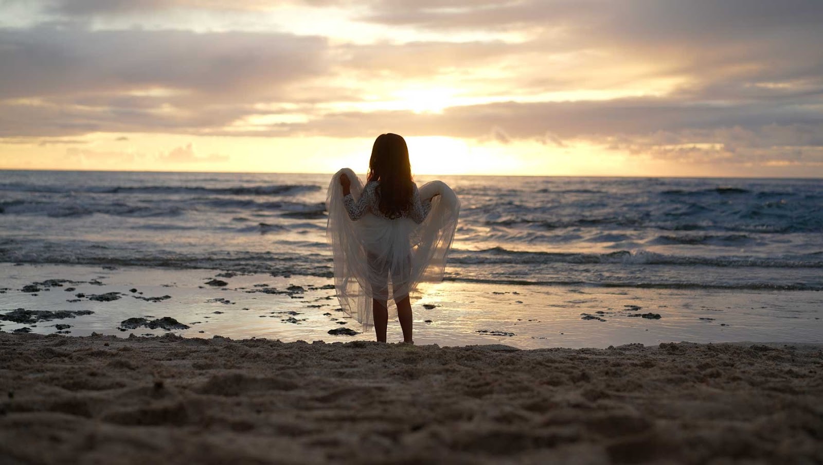 Cute daughter watching the sunset after a beach wedding