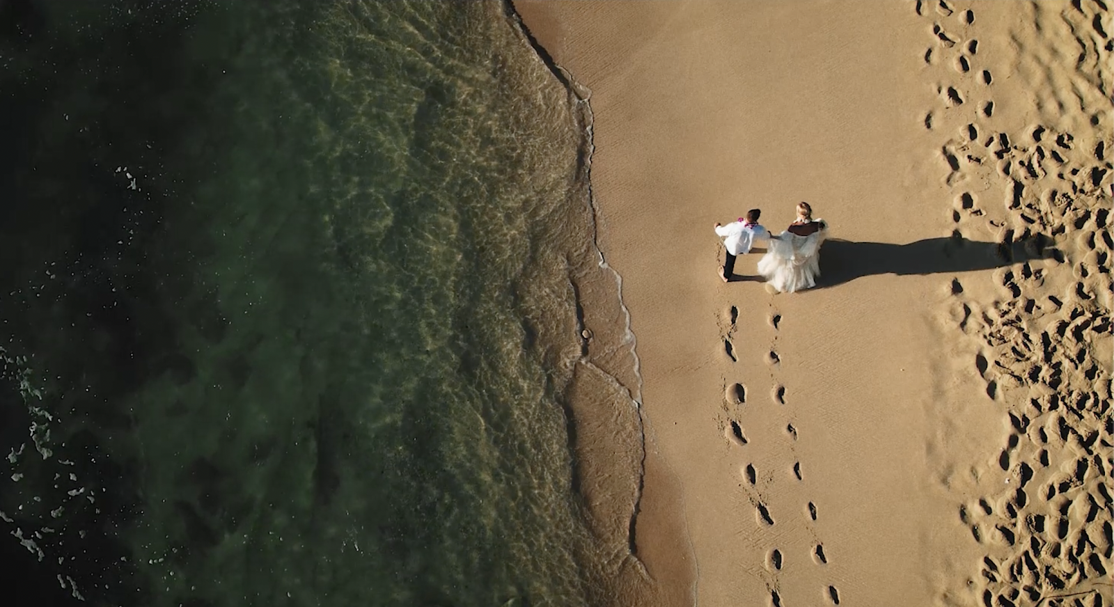 Drone shot of a wedding couple walking on the beach in Hawaii